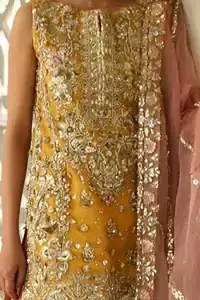 Amber shirt adorned with mainly light golden embellishment on neckline, hemline and side slits. Pink peach dupatta adorned with embellished border and stripes. Multiple color sharara adorned with border on hemline, stripes and motifs.