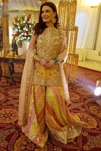 Amber shirt adorned with mainly light golden embellishment on neckline, hemline and side slits. Pink peach dupatta adorned with embellished border and stripes.