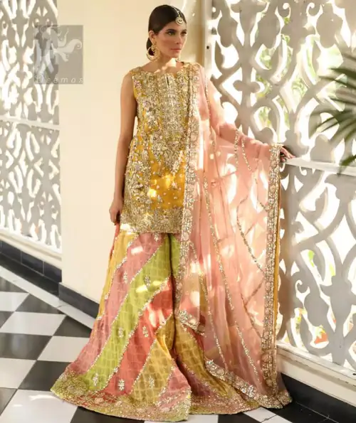 Amber shirt adorned with mainly light golden embellishment on neckline, hemline and side slits. Pink peach dupatta adorned with embellished