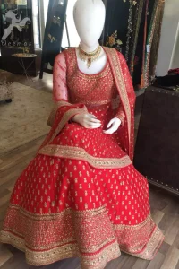 Simple but elegant deep red bridal blouse having dull golden and light antique embellishment. Appliqued with bright red fabric. Red lehengha having large borders of hand embellishment and small motifs spray above the hemline. Same border as on lehengha has been implemented on dupatta with motifs spray all over it.