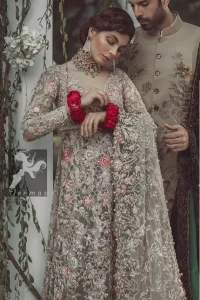 Light fawn front slits gown adorned with beautiful colourful embellishment. Red lehenga adorned with embellishment all over it. Dupatta in light pistachio having embellished border on sides and motif spray all over it and finished with piping.