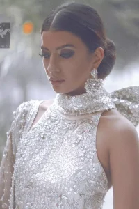 White choli / blouse having beautiful embellishment in white, silver and maroon brown. Halterneck design has been implemented on blouse / choli. White lehenga / skirt having heavy embellishment.