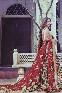 Frock having intricately embellished brown bodice and deep red frock embellished with tea pink, golden and brown shaded kora, dabka, naqshi, sequins, beads and pearls. This outfit is beautifully coordinated with brown embellished lehengha. Lehengha is embellished with a larger border. This outfit is enhanced by a thick floral embellished pattern. Back has small flowery pattern all over it. Dress comes with red dupatta decorated with four sided floral pattern. Wavy sequins pattern embellishment all over it.