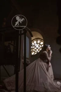 Ivory floor length Anarkali embellished with floral embroidery. Front and back bodice is fully embroidered with dull golden and antique shades of kora, dabka, tilla, pearls and sequins. There is beautiful cutwork and embroidery on sleeves cuffs and near the shoulders. Its hemline is allured with two delicate appliqued borders. One of them is of white pearls and the other one is of delicate embroidery.  This dress is artistically coordinated with simple ivory brocade lehengha and delicate tissue dupatta. Dupatta is adorned with cutwork and embroidery on pallu and there is small floral embellishment pattern on dupatta.