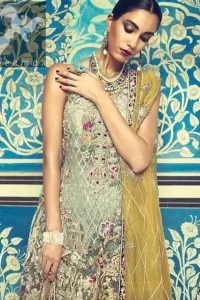 This shirt is decorated with resham threads, kora, dabka, tilla, sequins and pearls. The shirt is beautifully decorated with self embroidered criss cross pattern. It is further enhanced with embroidered scalloped border which adds to the look. It comes with brocade bell shaped trousers. It is beautifully coordinated with organza mehndi colored dupatta, allured with four sided embellished appliqued border.