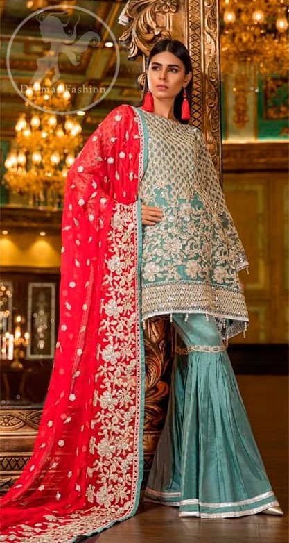 This shirt is adorned with floral embroidery.It is allured with silver and white kora dabka, tilla, sequins and swarovski. This outfit is decorated with intricate cut-work pattern on bodice and sleeves as well. It is beautifully paired up with blue smoke gharara pants. It is artistically coordinated with torch red dupatta which has one sided heavy embroidery and sprinkled with sequins all over it.