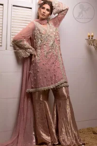 This outstanding copper rust angrakha meticulously highlighted with dull golden, tea pink and silver shaded kora, dabka , tilla, sequins and pearls. This dress is beautifully adorned with floral embroidery. It is decorated with small and large sized floral motifs. It is also embelished with beautiful tassels which adds to the look.It comes with brocade gharara pants. It is artistically coordinated with chiffon dupatta having sprinkled sequins all over it.