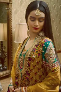 This outstanding angrakha shirt embellished with floral thread embroidery. It is allured with resham, kora dabka, tilla and pearls. Sleeves are decorated with gotta lace and floral embroidery. Embroidered applique on hemline adds to the look. It is beautifully paired up with magenta sharara with gotta criss cross patterns. It comes with chiffon goldenrod dupatta embellished with pea green applique.