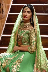 This outfit is embellished with gotta lace. It is meticulously highlighted with kora dabka, tilla, sequins and pearls. Sleeves are adorned with gotta lace in criss cross pattern. Boat-shaped neckline ornamented with floral motifs. It comes with hippie green lehenga adorned with floral embroidery. It is coordinated with chiffon dupatta embellished with applique and sprinkled sequins all over.