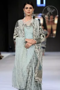 This outfit is a timeless beauty. The blouse is covered with gown embellished with silver gold kora dabka, Sequins and swarovski crystals.This exquisite gown is decorated with embroidered black applique and tassels on hemline.It comes with lehenga style bottom. This Outfit is beautifully coordinated with strip of material that wrapped around the blouse and draped across the front and over one shoulder?