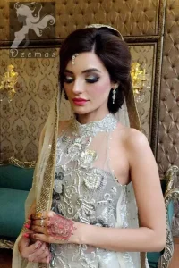 This outfit is a timeless beauty. It is heavily embellished with silver kora, dabka, sequins and swaronski crystals. This exquisite A-line frock is fully decorated with floral motifs patterns all over it. It is further enhanced with halter neckline.It comes with sharara which has small sized sprinkled floral motifs all over. This Outfit  is beautifully coordinated with matching dupatta with heavy embroidered borders and finished with piping.
