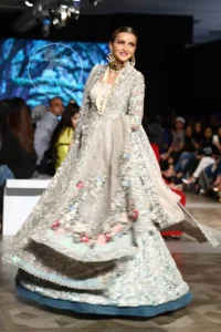 This outfit is a timeless beauty. It is heavily embellished with silver gold kora dabka, Sequins and swarovski crystals. This exquisite Pishwas is fully decorated with floral motifs patterns all over it. It is further enhanced with multiple colored Foral thread embroidery. The applique border of pishwas is ornamented with small silver pearls. It comes with embellished lehenga which has small sized sprinkled floral motifs all over. This Outfit is beautifully coordinated with matching Dupatta with heavy embroidered borders.