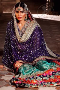 This unique bridal dress is beautifully sculptured with floral thread embroidery. It is meticulously highlighted with silver and antique kora dabka, tilla, sequins and pearls. It is artistically paired up with brocade gharara which is embellished with different color applique. It comes with chiffon dupatta which has four sided embellished border and sprinkled with sequins all over it.