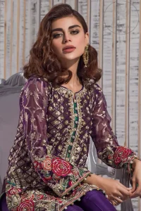 This outfit is beautifully sculptured with multiple color floral embroidery. The iridescent organza shirt is adorned with self print criss cross patterns. It is embellished with dull golden kora, dabka, tilla, and sequins work. Neckline is adorned with embellishments. It is artistically coordinated with chiffon dupatta with sprinkled sequins all over it. It comes with purple straight trousers.
