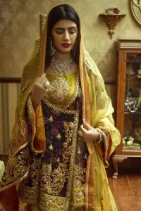 This  royal blue angrakha shirt is embellished with resham thread. It is meticulously highlighted with dull golden kora dabka, tilla,  sequins and pearls. Sleeves and neckline are adorned with gotta work as well. Hemline is allured with embroidered applique. It comes with embellished gharara which has sprinkled floral motifs. This Outfit is beautifully coordinated with yellow dupatta with heavy embroidered borders.