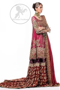 This bridal dress is adorned with floral embroidery.It is meticulously highlighted with dull golden and antique shaded kora, dabka, tilla, sequins and pearls. It has beautiful embellished bodice and U-shaped neckline which adds to the look.Sleeves are embellished with embroidered applique. Hemline is adorned with beautiful tassels. It is artistically coordinated with brocade embellished gharara. Gharara is allured with beautiful contrast of rust and plum color. It comes with pink dupatta which is decorated with embroidered borders and sprinkled sequins all over.