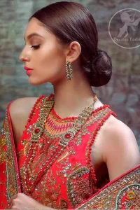 This dress is beautifully sculptured with floral thread embroidery. The halter shaped neckline meticulously highlighted with antique shaded kora, dabka, tilla, sequins and pearls. The shirt is ornamented with multiple color thread embroidered applique. It comes with chiffon dupatta which has four sided embellished border and sprinkled with sequins all over it. It is beautifully paired up with brocade sharara.