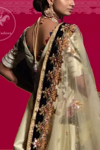 This signature angrakha is crafted with raw silk featuring hand embroidery with elegant zardoze work. The sharara with it is made of brocade with applique detail on bottom done with kora dabka, kundan and tilla work. It comes with ivory dupatta adorned with black applique and heavy embellished borders on all sides.