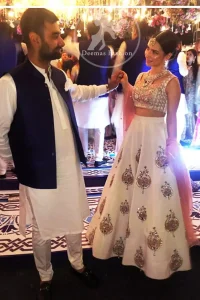 The blouse is beautifully embellished with cutwork embroidery enhanced with silver gold kora dabka, kundan and sequins work. It is paired up with ivory lehenga with colorful pattern embellishment ornamented with kora dabka, and colorful thread embroidery. It comprises with peach dupatta sprinkled sequins all over.