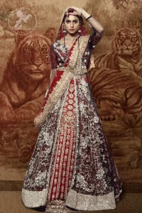 This dress is timeless beauty. Black floor length net paneled gown is beautifully embellished with silver kora dabka, tilla, pearls and sprinkled sequins all over. It comprises with maroon blouse and skirt. The skirt is ornamented with floral motifs done with silver gold kora dabka, tilla, kundan and sequins work. This outfit is coordinated with maroon dupatta with embroidered borders on all four sides and sequins work on the ground.