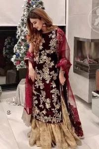 Take a step towards refreshing your wardrobe with maroon velvet dress. This maroon shirt is heavily embellished in the front with silver gold kora dabka, kundan, tilla and sequins. Finished with golden brocade self-printed gharara. This outfit is beautifully coordinates with maroon dupatta with embroidered borders on all four sides .