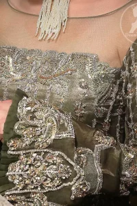 The beautiful bodice is decorated with intricate stones and sequins. It is further enhanced with vertical lines and floral motifs done with kora dabka, tilla, sequins and colorful thread work. Paired up with embroidered bell bottom. This outfit is beautifully coordinated with olive green dupatta with embellished borders on sides and sprinkled sequins.