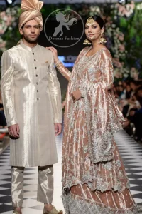 This dress is beautifully decorated with heavy embroidery. It is highlighted with kora, dabka, tilla, sequins and pearls. It comes with embroidered sharara. It is coordinated with tissue dupatta which is sprinkled with sequins all over it. It is further furnished with four sided scalloped border.