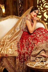 Reflecting royalty and the majestic beauty of statuesque shape and silhouette this bridal dress is perfect for your special day. Feel glamorous in this floor length maxi with fascinating embellishment around the neckline with golden kora dabka, pearls and sequins. It is further enhanced with floral motifs and heavy embroidered bottom. The hemline is decorated with heart shape motifs all around the bottom of maxi. It comprises with brocade pajama and golden dupatta having four sided embroidered borders and sprinkled small motifs on ground.