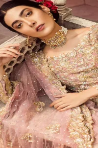 The grand gold bridal stands out due to its uniqueness and the perfect fusion of modern cut and traditional embroidery. It is highlighted with dull golden and silver kora, dabka, tilla, sequins and pearls. The frock is fully embellished from daman. It is coordinated with matching lehenga which has sprinkled floral motifs. This outfit is paired up with net dupatta which is sprinkled with sequins and small floral motifs. It is furthermore enhanced with four sided scalloped border.
