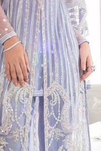 Steal the moment with our cold purple floor length gown emphasized with traditional neckline and intricate floral daaman enhanced with silver kora, dabka and sequins. It is adorned with fully embellished neckline and verticle lines, finished with floral thread embroidered hemline. Scalloped bell sleeves with tassels give it a perfect look. It comes with raw silk trousers. It is coordinated with chiffon dupatta which is sprinkled with sequins all over it.