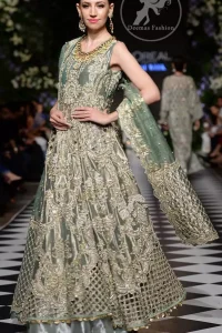 This dress is beautifully decorated with heavy embroidery. It is highlighted with dull golden kora, dabka, tilla, sequins and pearls. Fish lehengha is fully embellished.Blouse is scalloped. It comes with beautifull upper gown, sprinkled with sequins all over it. It is coordinated with chiffon dupatta which is sprinkled with sequins all over it.