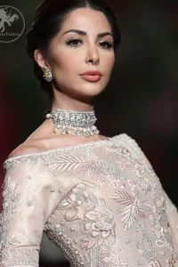 The bridal stands out due to its uniqueness and the perfect fusion of modern cut and traditional embroidery. This dress is beautifully decorated with heavy embroidery. It is highlighted with kora, dabka, tilla, sequins and pearls. It comes with embroidered sharara. It is coordinated with tissue dupatta which is sprinkled with sequins all over it. It is further furnished with four sided scalloped border.