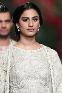 Go for this trendy dress. This dress is heavily embellished with floral and geometric styled embroidery decorated with silver kora, dabka, swarovski and pearls. Gown is enhanced with scalloped border decorated with thread clusters finishing. Third quarter sleeves are embellished with floral motifs all over along with tassels at the end. Trousers is magnificently decorated with cutwork. It is coordinated with tissue dupatta which is sprinkled with sequins all over it.