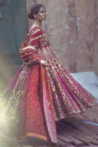 Captured in traditional silhouette, this frock bursts of vibrant colors and sumptuous details of zardozi, kora and dabka is a perfect Mehndi ensemble. The detailed kundan work on neckline and vertical panel stripes ornamented with gold kora and dabka embroidery on the bodice and comprises with churidar pajama. Complete the look with red self printed shawl and embellished pallu border to give it a perfect look.