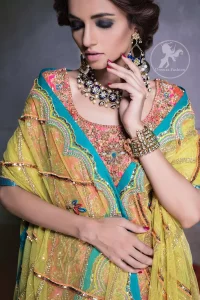 Our tea rose shirt with exquisite embellished neckline and back neckline in kora, dabka sequins and intricate thread work. The daaman is emphasized on intricate floral details that gives perfect ending to this shirt. It is coordinated with farshy gharara decorated with embroidery. The gradient turmeric dupatta has crisscross pattern and floral motifs scattered. It is finished with jamawar piping all around the edges.