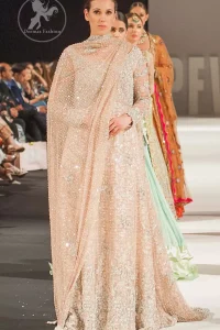 This dress is beautifully decorated with heavy embroidery. It is highlighted with dull golden kora, dabka, tilla, sequins and pearls. Fish lehengha is fully embellished.Blouse is scalloped. It comes with beautifull upper gown, sprinkled with sequins all over it. It is coordinated with chiffon dupatta which is sprinkled with sequins all over it.