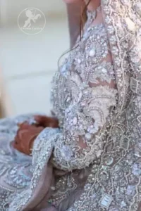 The grand gold bridal stands out due to its uniqueness and the perfect fusion of modern cut and traditional embroidery. This dress is beautifully decorated with heavy embroidery. It is highlighted with kora, dabka, tilla, sequins and pearls. Style it up with embellished wait belt. It comes with brocade pajama. It is coordinated with tissue dupatta which is sprinkled with sequins all over it. It is further furnished with four sided thick embellished border.