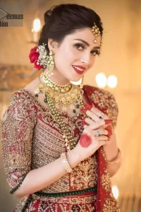 A bed of red roses translated onto a dress decorated, elaborate and flamboyant elegance. This bridal wear is perfect for your big day. The bridal stands out due to its uniqueness and the perfect fusion of modern cut and traditional embroidery. The blouse is beautifully ornamented with floral embroidery and swarovski crystals lines. Finishing with green dangling beads ball at the end. Pair it up with beautiful embroidered lehenga adorned with golden kora, dabka, tilla and sequins. Furthermore it is highlighted with geometric patterns and applique details on lehenga. It is coordinated with beautiful dupatta with thick matha patti border on two sides and intricate thin border on remaining two sides.