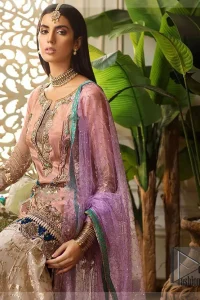 Add some super cool twist to your look with this outfit on your nikah. Gussy up in this luxuriously designed shirt emboldened with intricate embroidery along with beautiful rich patterns and delicate applique details at the daaman. Furthermore this super stunning shirt is made of rich floral embroidery which is further enhanced with zardosi work. Having full length sleeves adorned with scalloped finishing. Style it up with artfully coordinated ivory sharara finessed with lace and applique details at the bottom. The outfit is beautifully coordinated with light purple dupatta with embellished lace borders on all four sides and scattered sequins all over.