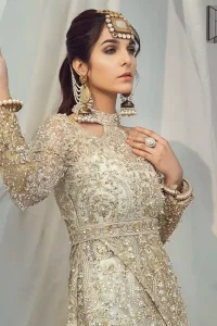 Brighten up your look with this glamorous halter neckline maxi perfect for your wedding day or evening ensemble. This glamorous attire accentuated with finest zardosi work and cut work borders. The bottom of the maxi has small circular motifs adorned with golden pearls and detailed scalp border gives a perfect ending to this maxi. Having full length sleeves ornamented with kora, dabka and tilla embroidery with sequins spray all over. Style it up with artfully coordinated ivory straight trousers finessed with organza details at the bottom.