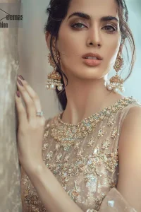 This bridal dress executing heavily hand crafted art of zardosi, kora and dabka with splashes of golden and silver is a classical visit to feminine personification. The heavenly handcrafted lehenga showcases the traditional art of zardozi, nakshi, kundan, kora and dabka; adorning the intricate and meticulous hand embellishments giving it a wholesome gentle stance paired with a regal gold sleeveless blouse. The bottom of the lehenga is enhanced with embellished applique with zardosi work and resham embroidery. It comprises with organza dupatta having four sided matha patti style border and scattered sequins all over it.