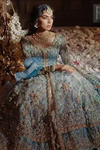 Reflecting royalty and the majestic beauty of statuesque shape and silhouette this dress is perfect for your walima and engagement function. Add some super cool twist to your look with this subtle colors in intricately embroidered frock. Capture the attention with fascinating embellishment on neckline with silver and dull golden kora, dabka, pearl and sequins. Having full length sleeves adorned with floral motifs. It comprises with ivory sharara. Thin border with floral motifs on all four sides of the dupatta which have gold tila embroidery with kora and dabka. 