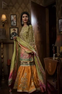 Brighten up your look with this beautiful mehndi dress comes with a beautiful parrot green shirt. This shirt is adorned with light gold kora, dabka, tilla and sequins work, furthermore the hemline is enhanced with applique embellishment. Paired it up with traditional jamawar gharara ornamented with zardozi work and finished with lace embellished border. It is coordinated with parrot green dupatta dyed from pallu in two colors and adorned with applique embellished border.