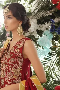 Tradition meets modernity. Boost your confidence and style in this glamorous attire accentuated with finest zardozi work embroidery and scalloped borders with dandling pearls. This maroon sleeveless shirt is ornamented with golden and light golden zardozi work. The scalloped hemline is decorated with dangling pearls. Style it confidently with maroon sharara adorned with beautiful gota work. It is paired with an ethereal maroon dupatta with scattered sequins all over and four sided applique borders.