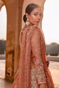 You are all set to make a lasting impact with the divine royalty of this dress. This garment is sure to make you look like glamorous with immaculate work covering every inch of the pishwas with multiple panels. This pishwas made of zardozi work with scalloped hemline and applique is everything that you need for your festivities. The brocade lehenga is beautifully adorned with thick embellished bottom with zardozi work in the shades of silver and gold. Style it up with peach organza dupatta with criss-cross patterns and floral booties on borders. This is an ensemble that deserves to be flaunted.