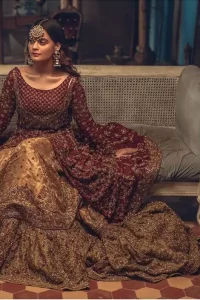 This wedding season, create a blissful aura with the treasure of love and elegance. An artistic vision of classic style and luxurious detailing, transpire into a truly romantic and iconic bridal for your big day. The front open floor length maxi is adorned with unique geometric patterns around the neckline and rest of the maxi is ornamented with floral embroidery. The kora, dabka, tilla and pearls embroidery is done in the shade of tan. Compliment the look with wide flared lehenga. The combination ofgolden with maroon is absolutely breathetaking. The dupatta incorporates beautifully designed borders on all four sides and sprinkled sequins to give it a perfect maharani look.