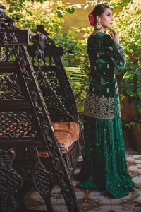 This mehndi outfit is a true example of decorative and ornamental expression stylized in a contemporary way. The dress comes with a bottle green velvet shirt with beautiful embellished motifs on the ground and vertically worked lines and it finished with a thick embellished border with silver zardozi work. Pair it up with bottle green crushed sharara adorned with scattered sequins all over. To complete the look, go with chiffon dupatta decorated with sequins spray all over.