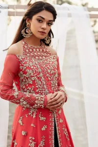 This outfit brings drama and playfulness to traditional frock and Sharara with a modern approach. Drape yourself to perfection for the classic affair in this flattering front open ensemble festooned with intricate zardozi hand embroidery work and motifs. The frock is furthermore adorned with halter neckline and comprises with overlaped bodice. Embellishment is done with zardozi embroidery in silver color. This outfit is comprises with bottle green velvet sharara and coral chiffon dupatta with sequins spray all over.