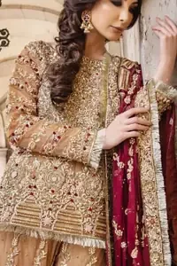 Picturing your bridal in a glowing fawn color. Featuring beautiful handwork, this outfit has a delicate arrangement of hand embellished geometric patterns with pearls and crystals on the bottom. Refined craftsmanship is at its best with hand embellished bodice which is laden with zardozi work. This outfit is paired with organza gharara with embroidered bottom and kiran lace, and maroon dupatta ornamented with geometric patterns along the length, making it a statement piece. Furthermore it is also enhanced with kiran lace on all four sides.