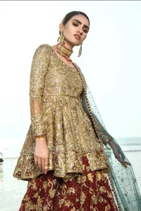 This wedding season, create a blissful aura with the treasure of love and elegance. An artistic vision of classic style and luxurious detailing infused with a bohemian spirit, transpire into a truly romantic and iconic bridal for your big day. The golden double layered peplum is heavily laden with zardozi and the perfect blend of traditional flamboyance and modern elegance in design. Pair it up with maroon lehenga enhanced with golden zardozi work. To complete the look, go with teel dupatta scattered with sequins all over the ground and heavily embellished borders to give it a perfect maharani look.